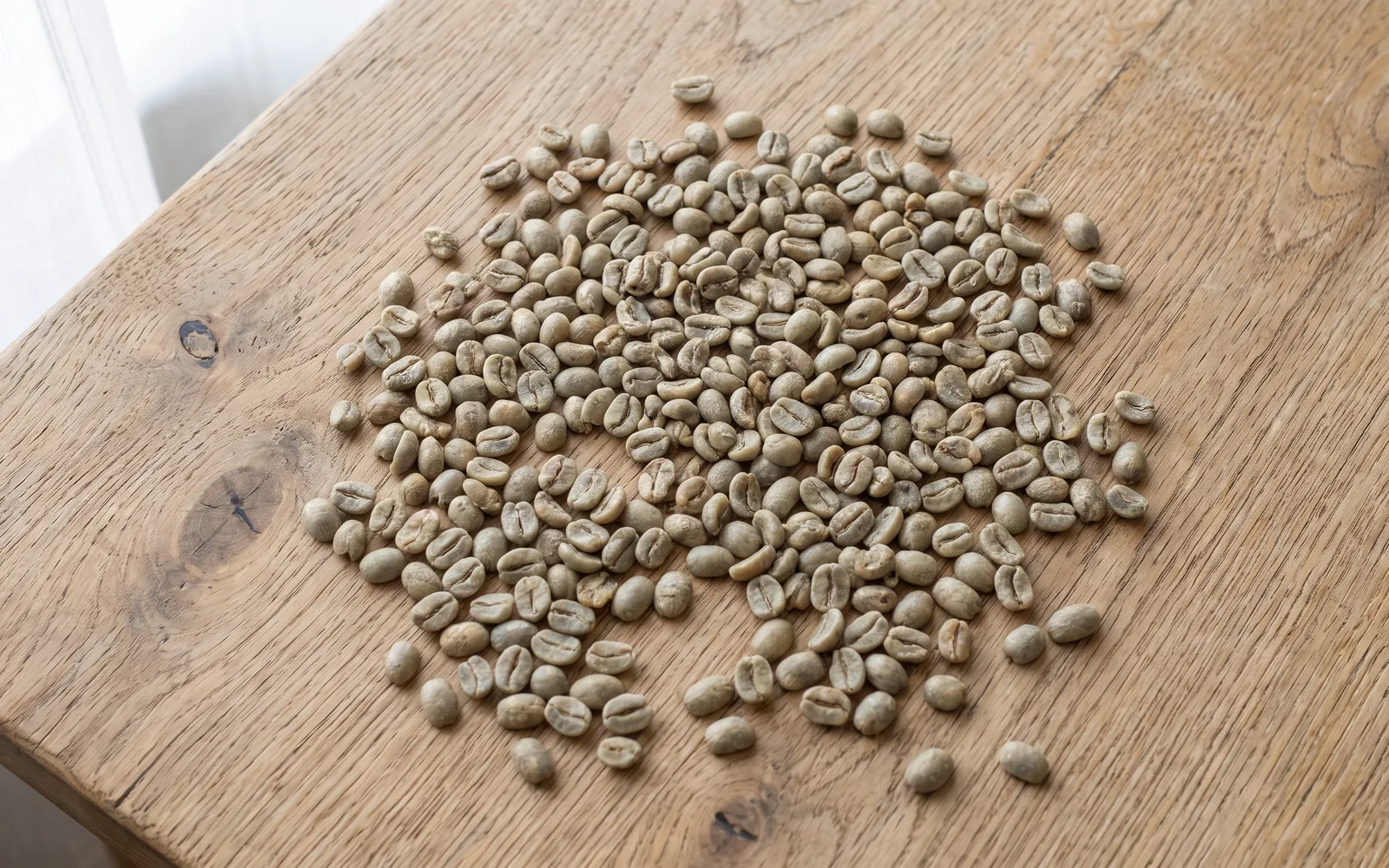 Granos de café verdes, sin tostar, sobre una mesa de madera